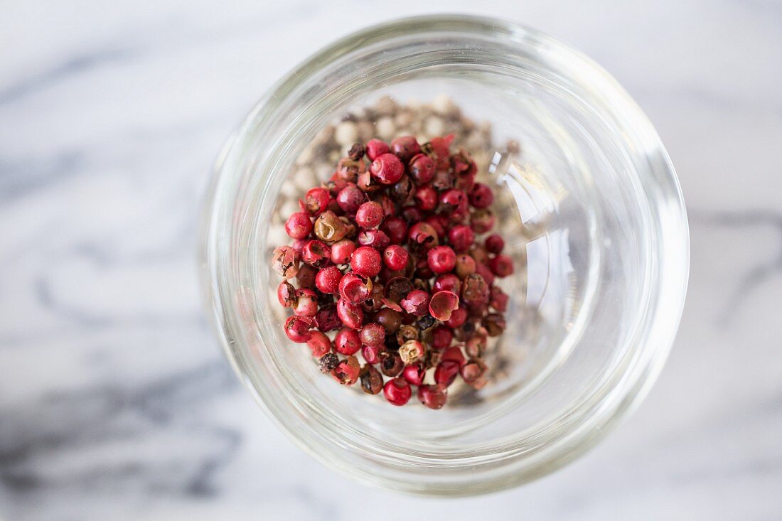 Red peppercorns in a glass on a marble surface