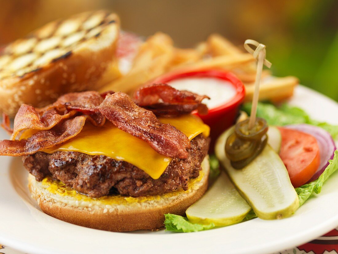 A bacon cheeseburger with salad and fries