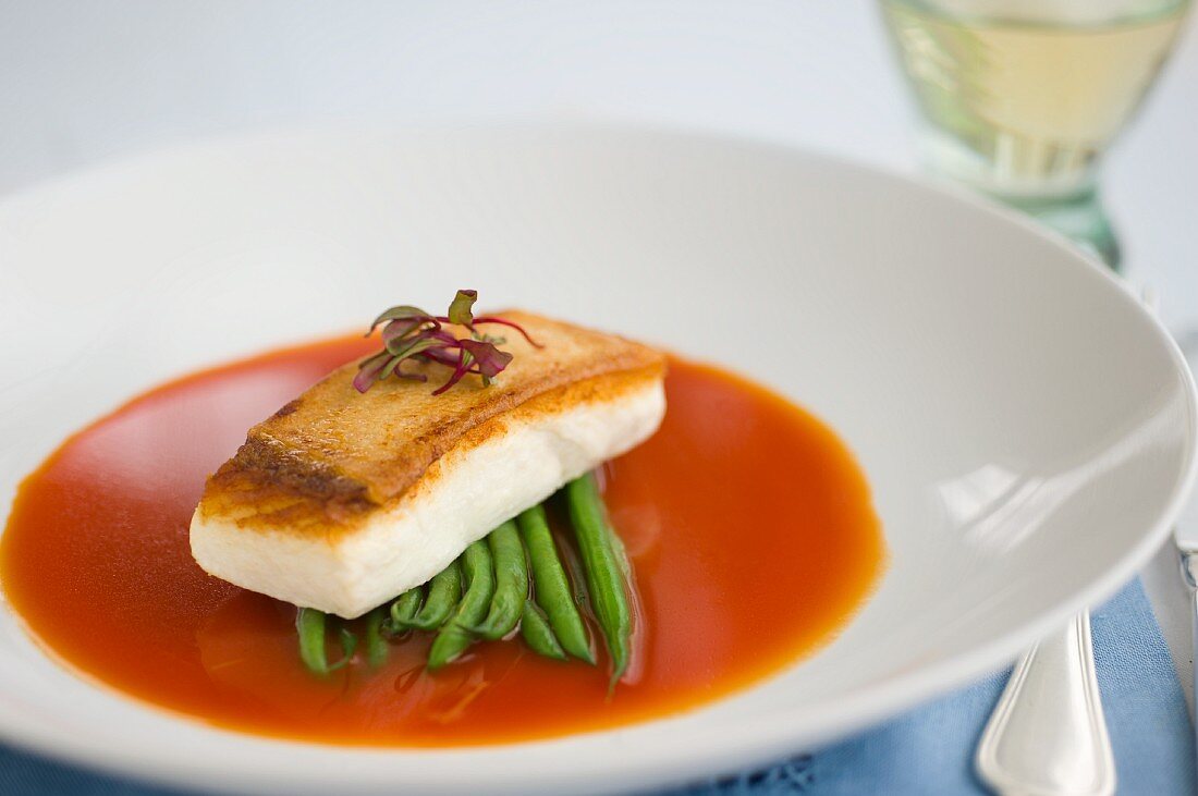 A halibut fillet with green beans in tomato consommé