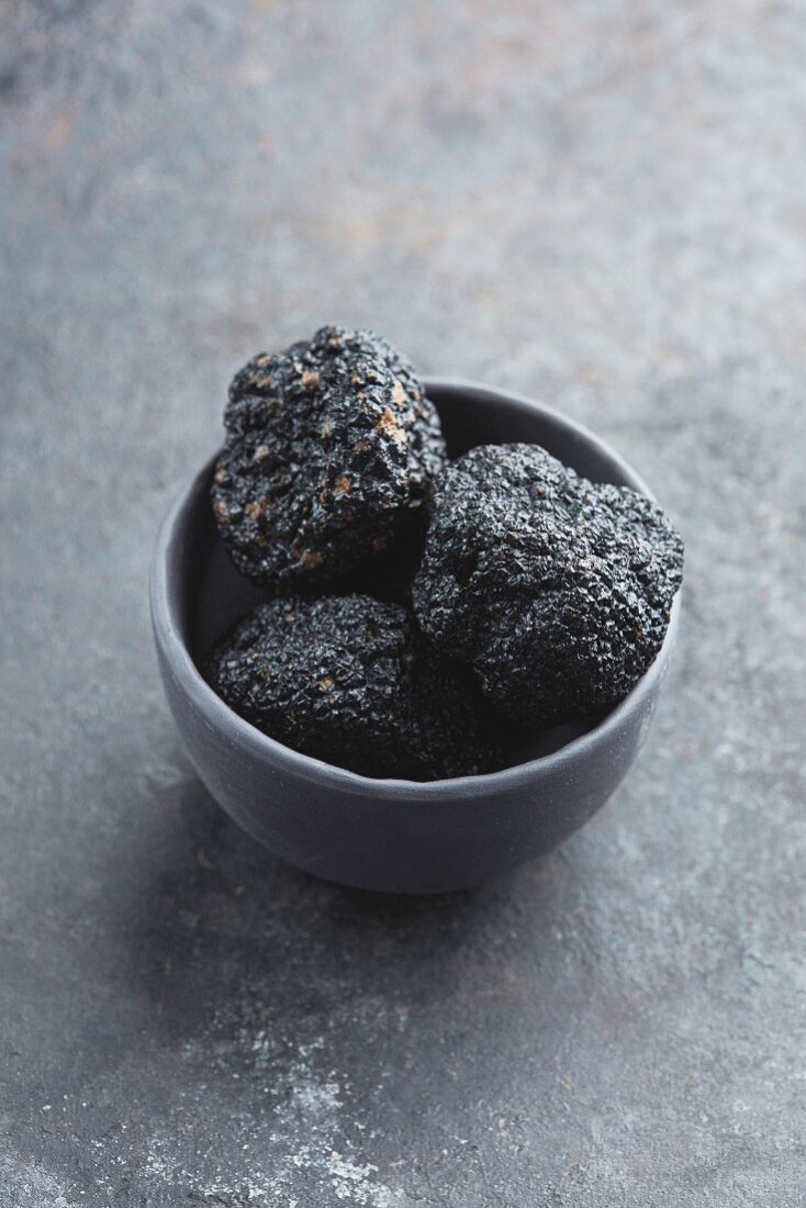 Three black truffles in a grey bowl