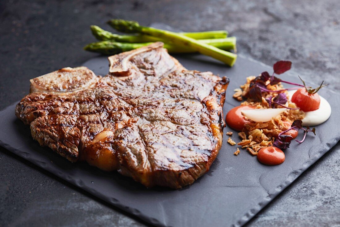 A fried beef steak with side dishes, served on a slate plate