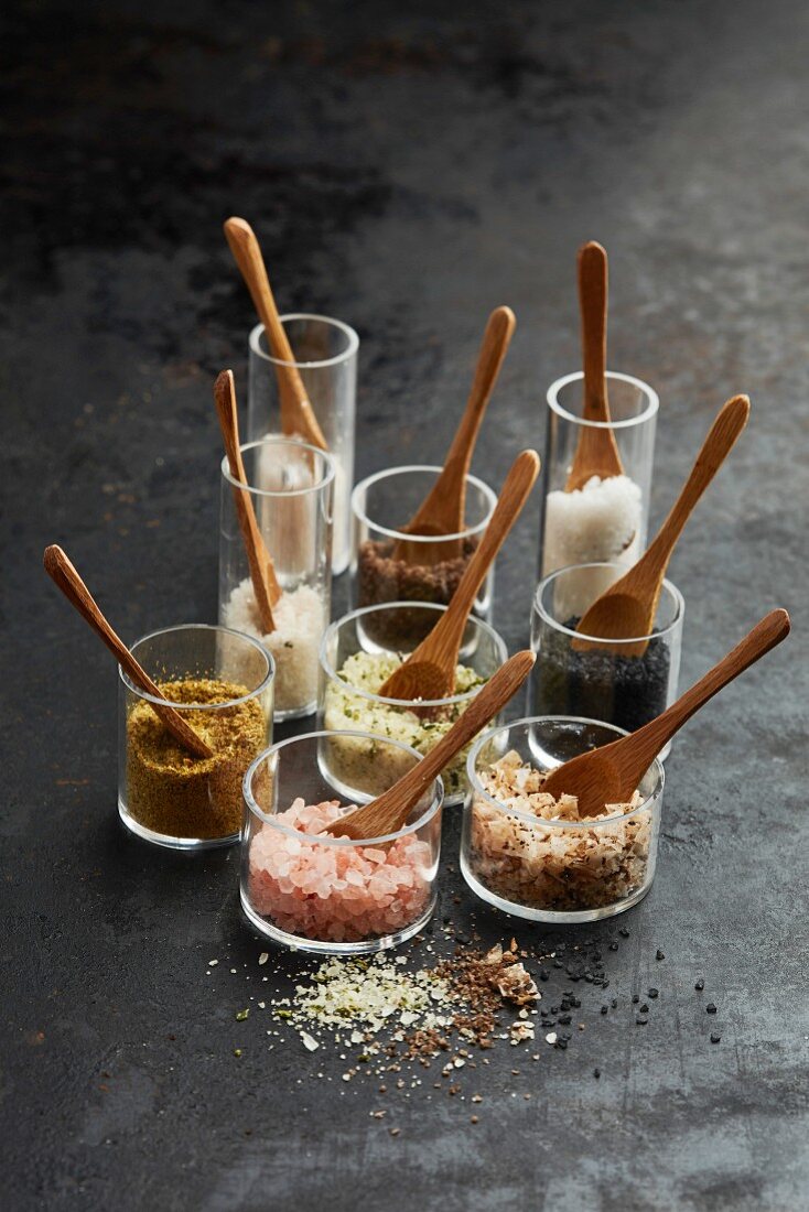 A still life of different salt varieties in glass jars with wooden spoons