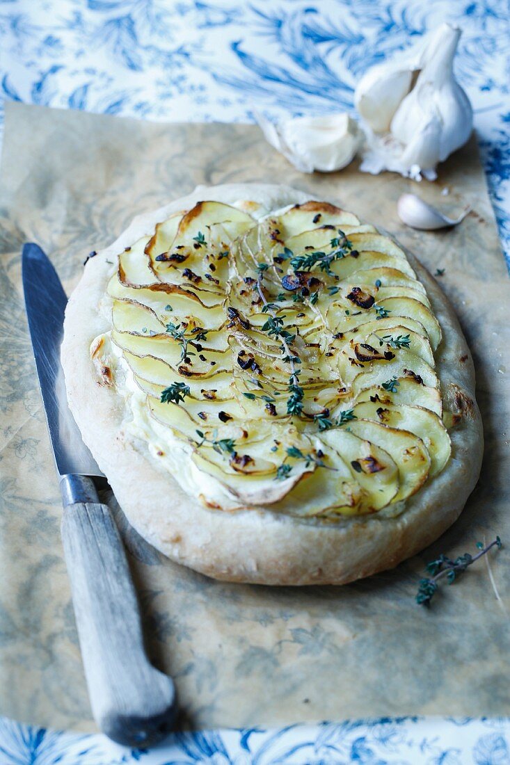 Pizza with fresh cheese, garlic, sliced potatoes, and thyme