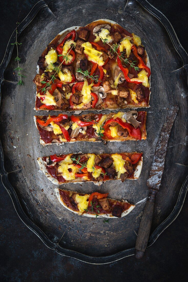 A spelt and linseed pizza base with peppers, mushrooms, tofu and vegan cheese substitute