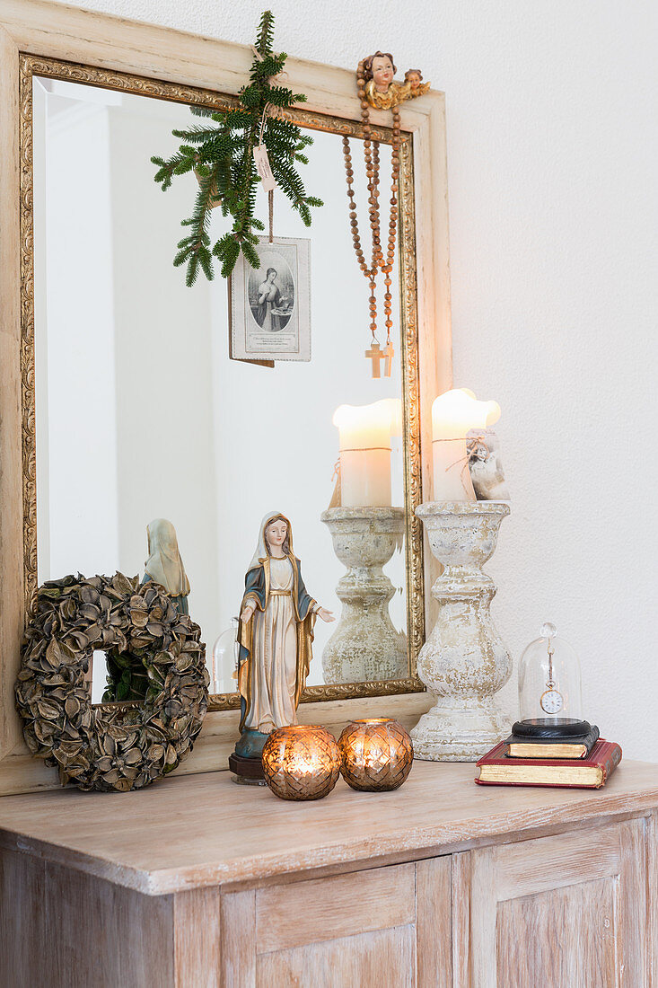 Madonna figurine, arrangement of candles and large mirror on cabinet