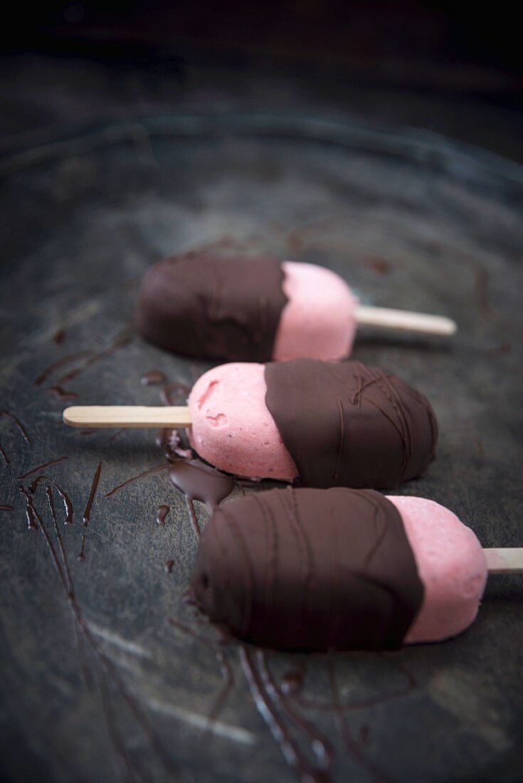 Strawberry ice cream, partially covered with dark chocolate (vegan)