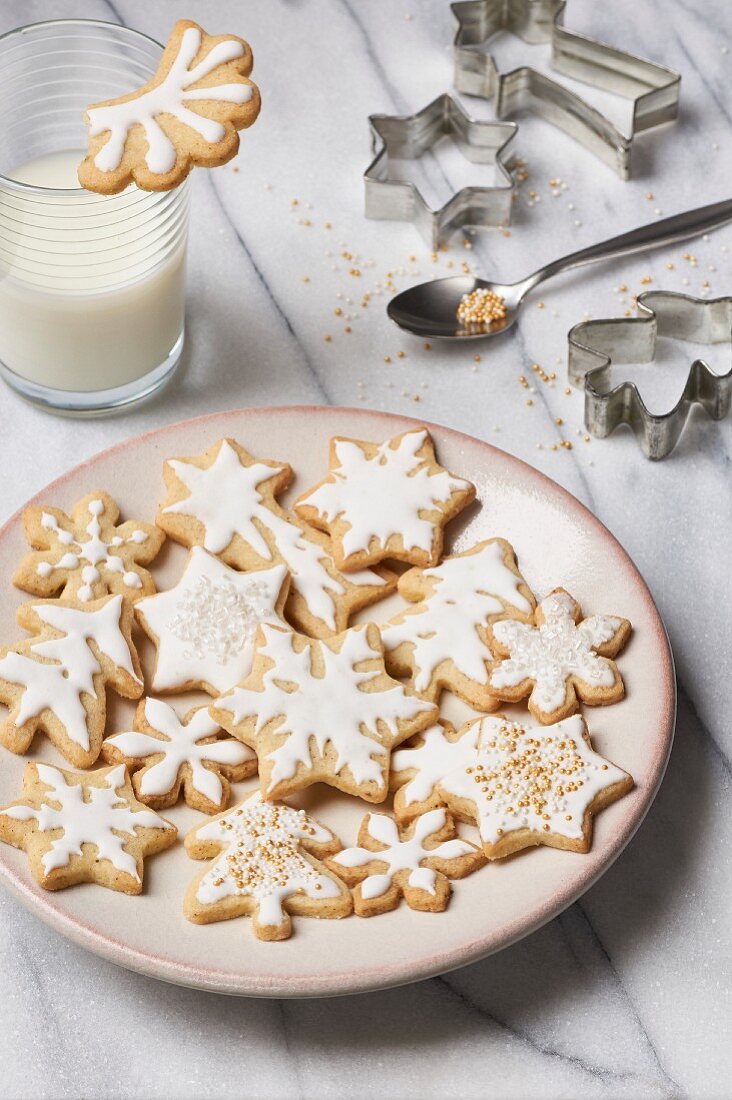 Butterplätzchen, weihnachtlich mit Zuckerglasur verziert, mit Milchglas und Ausstechförmchen