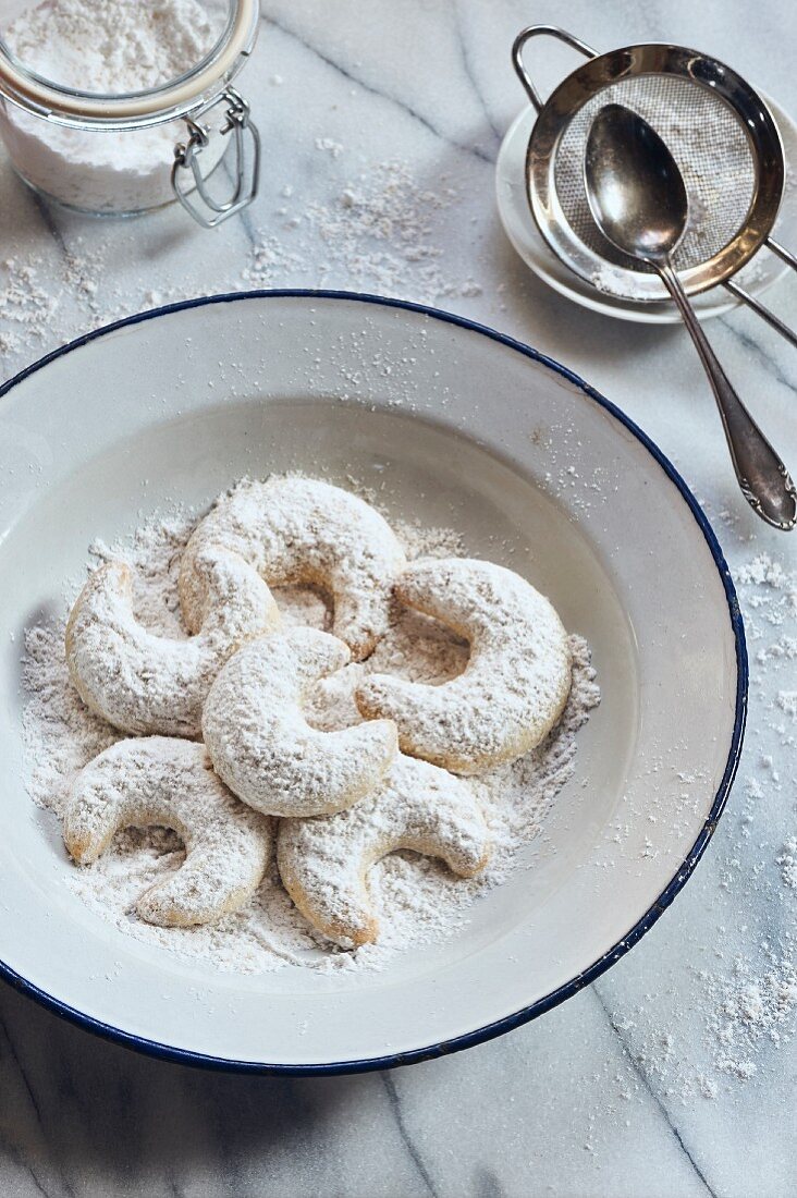 Vanilla horns with powdered sugar on an enamel plate