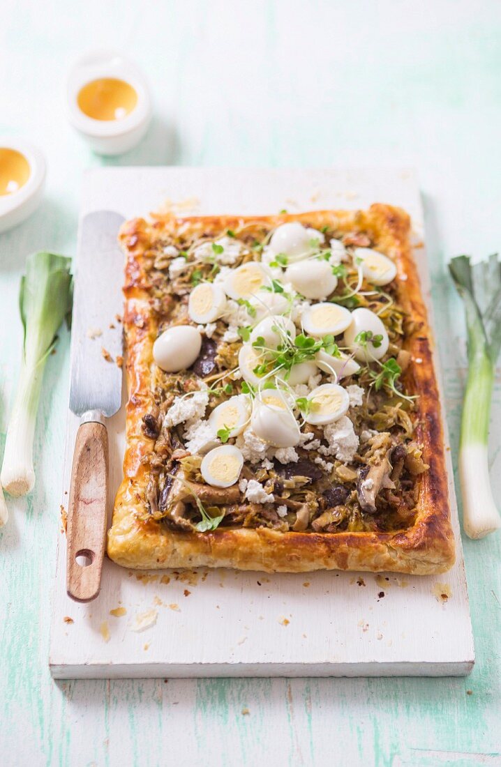 A savoury puff pastry tart with leeks, wild mushrooms, bacon and quails eggs