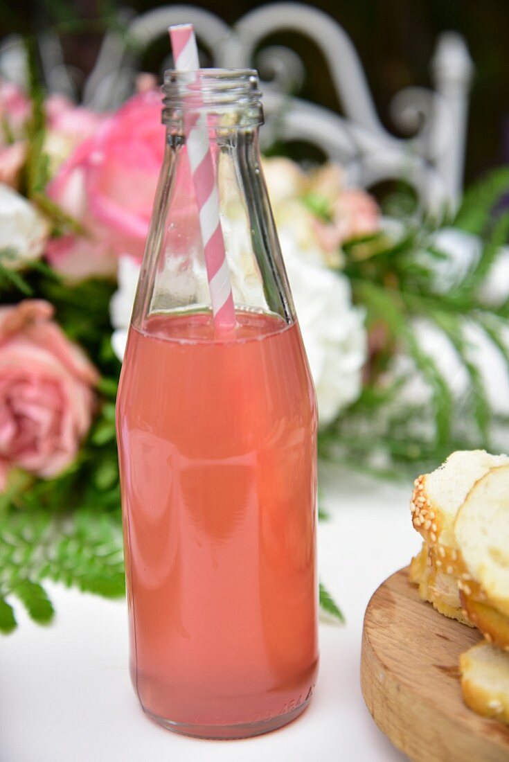 Pink lemonade in a glass bottle with a drinking straw