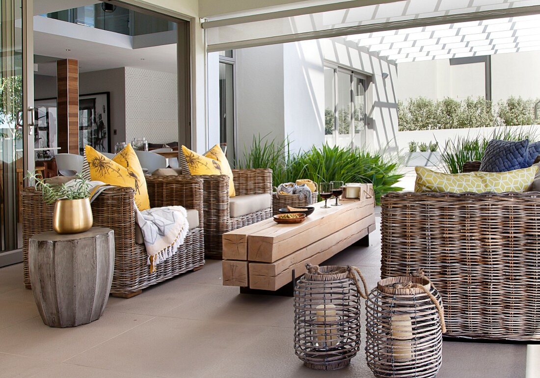 Wicker furniture and rustic coffee table made from untreated wooden beams on patio