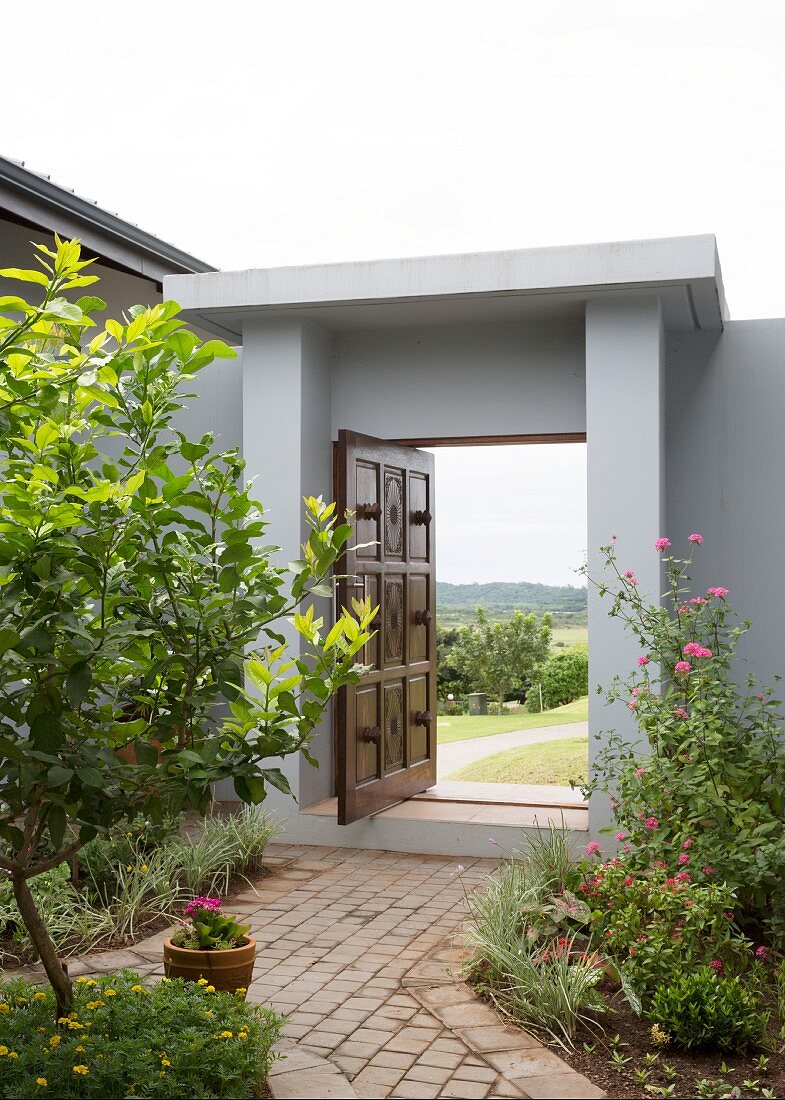 Open wooden door in modern grey garden wall