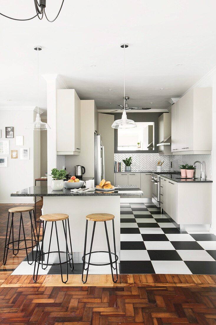 weiße Einbauküche mit Küchentheke und schwarz-weissen Bodenfliesen