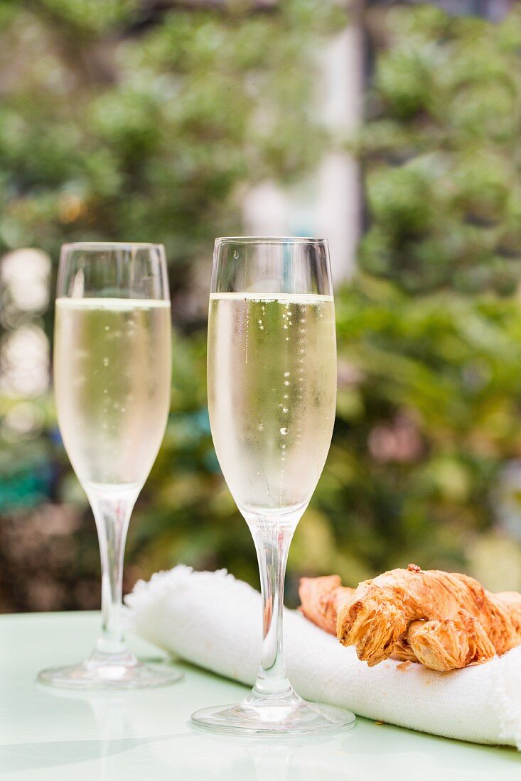 Two glasses of Prosecco on a table outside with large cheese straws