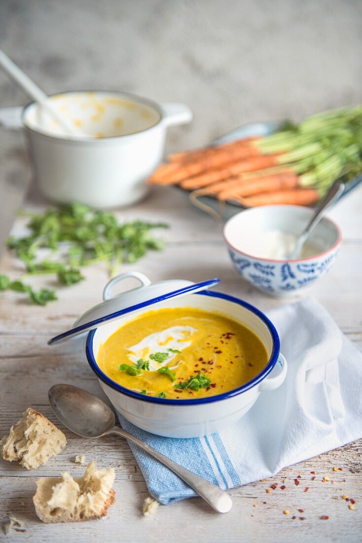 A bowl of carrot, corainder and coconut soup with bread