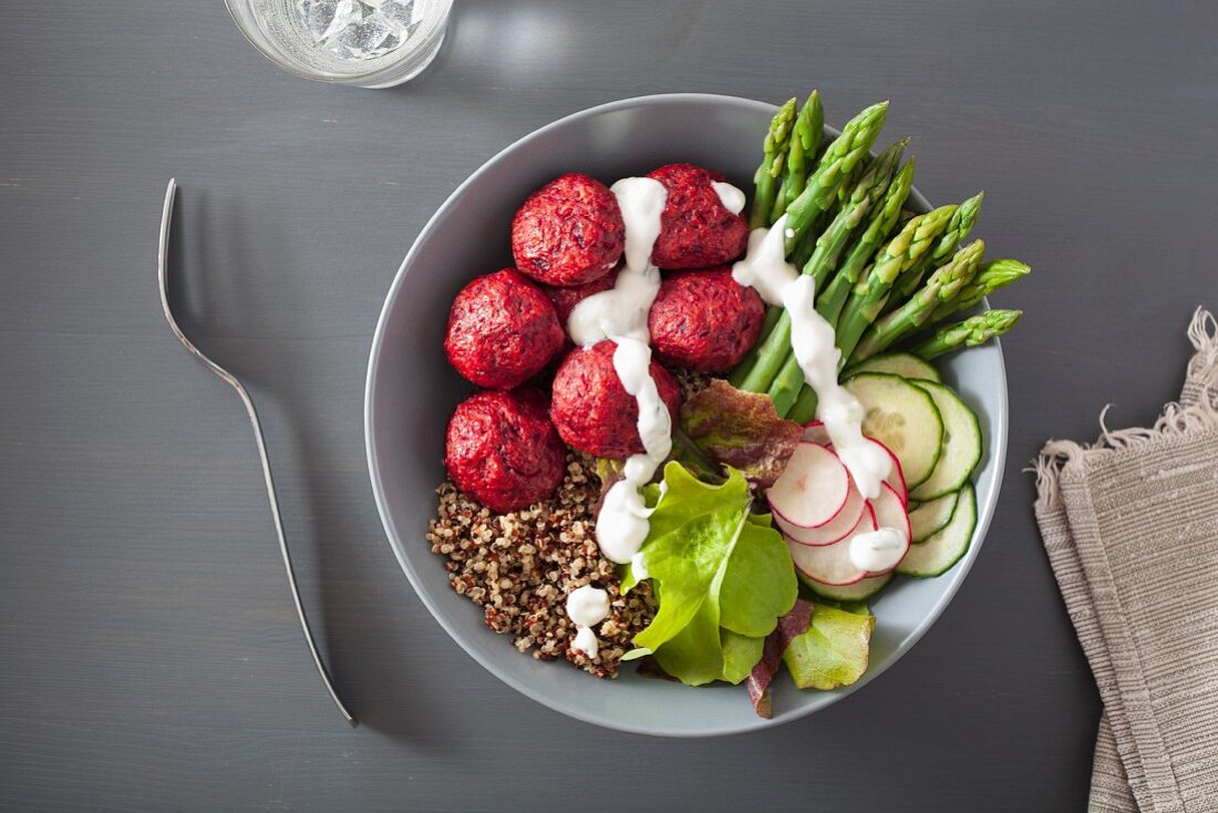 A beet falafel, quinoa, asparagus, radish, cucumber and yogurt dressing bowl