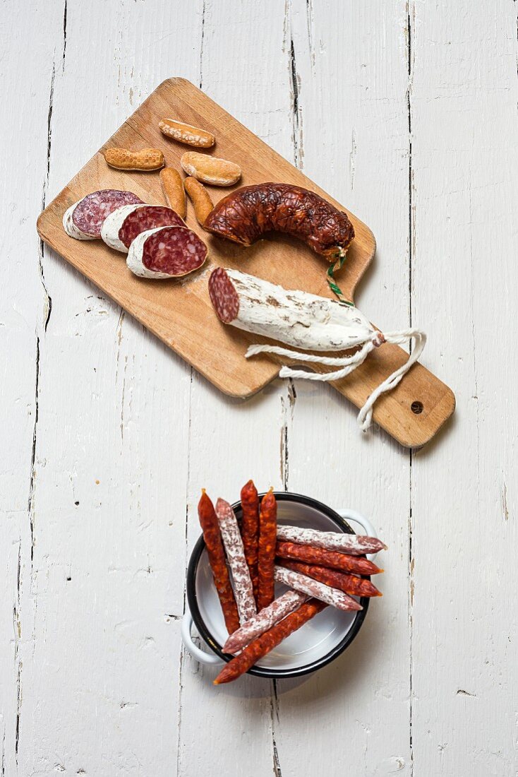 Various Spanish sausages in an enamel dish and on a wooden board (top view)