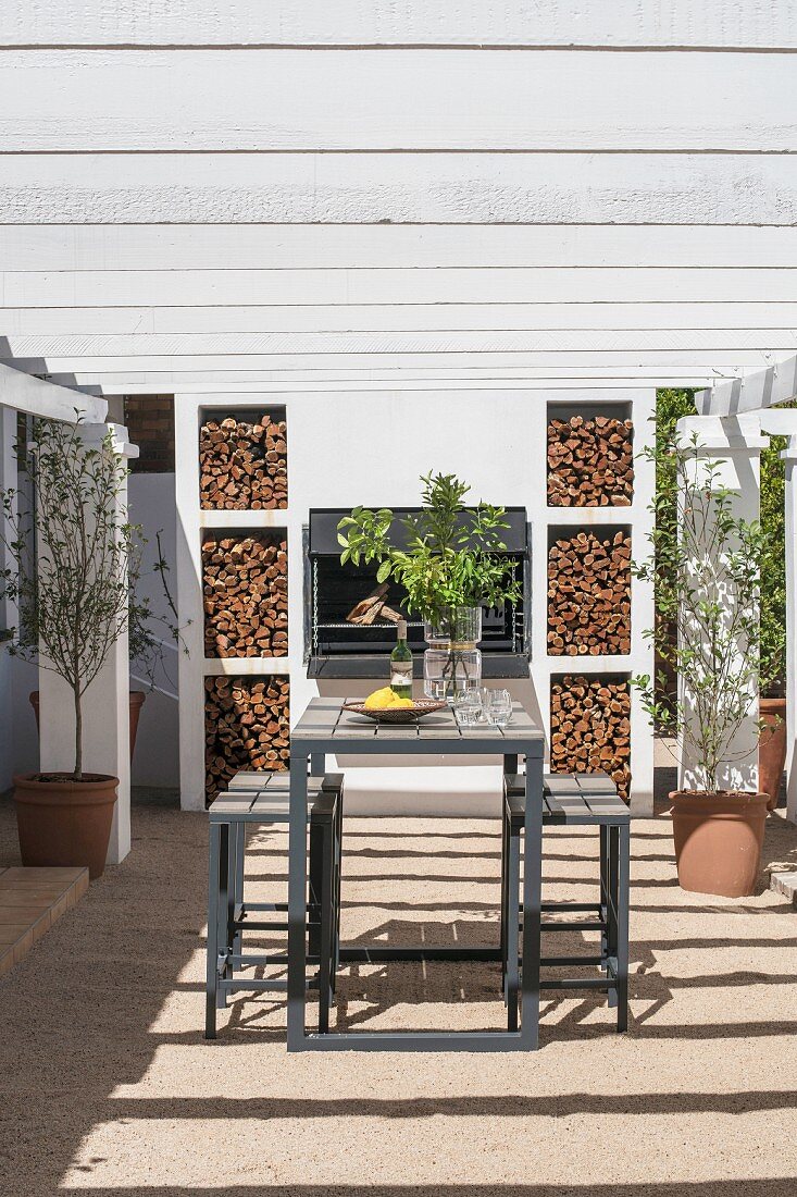 Wooden table, bar stools, barbecue and pergola on terrace