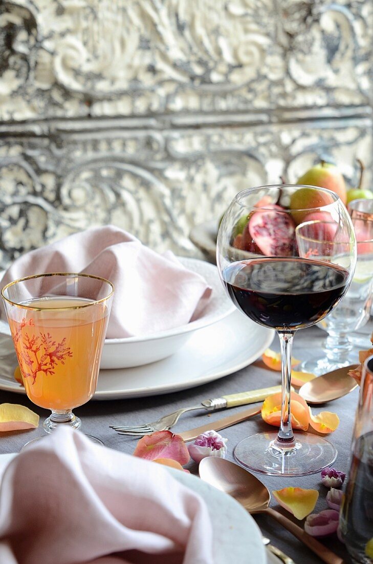 Rotweinglas und Cocktail auf gedecktem Tisch zum Muttertag