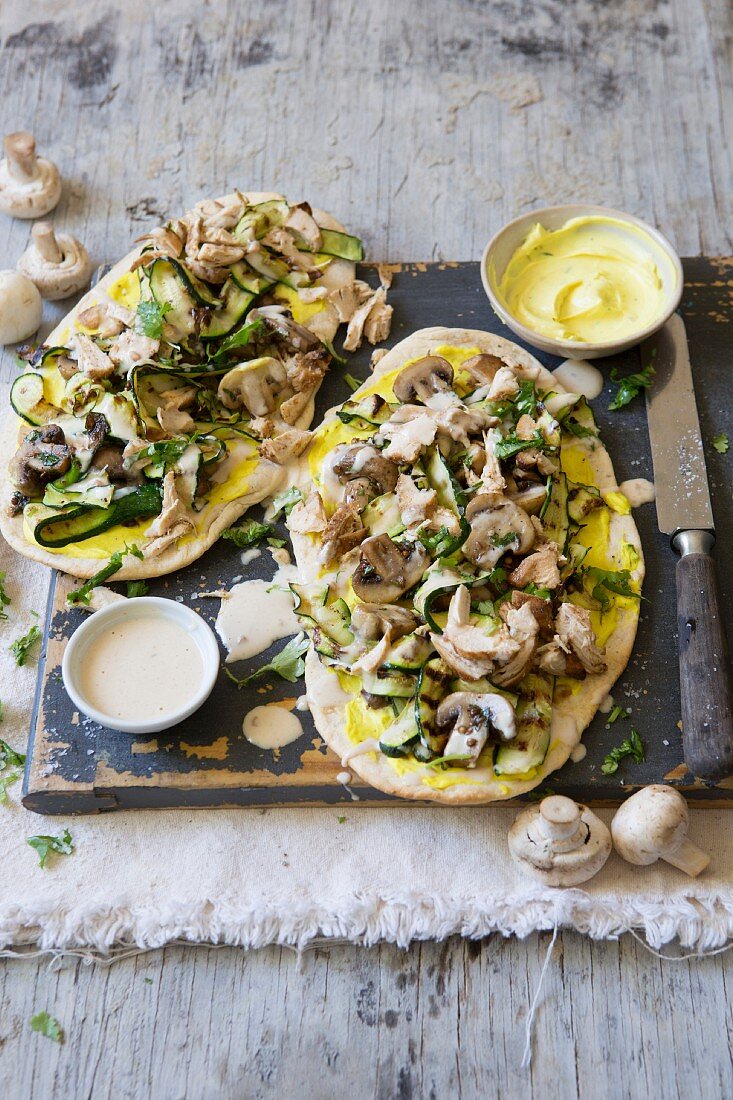 Naan pizzas topped with chicken and vegetables, with peanut and coconut sauce