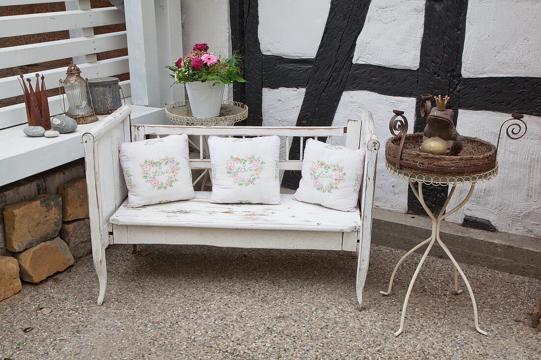 Cushions on shabby-chic bench against half-timbered wall
