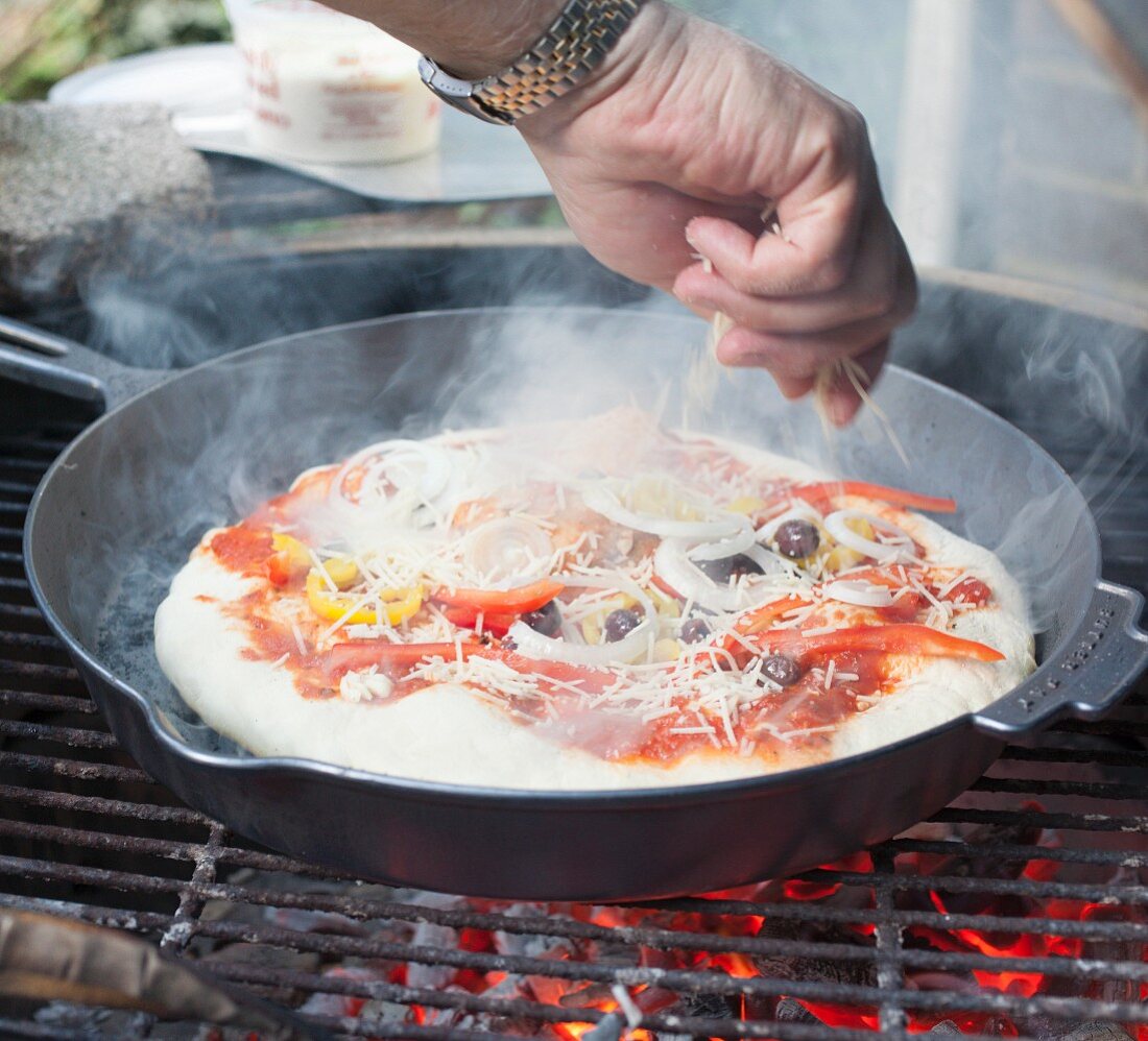 A pizza cooking on a grill