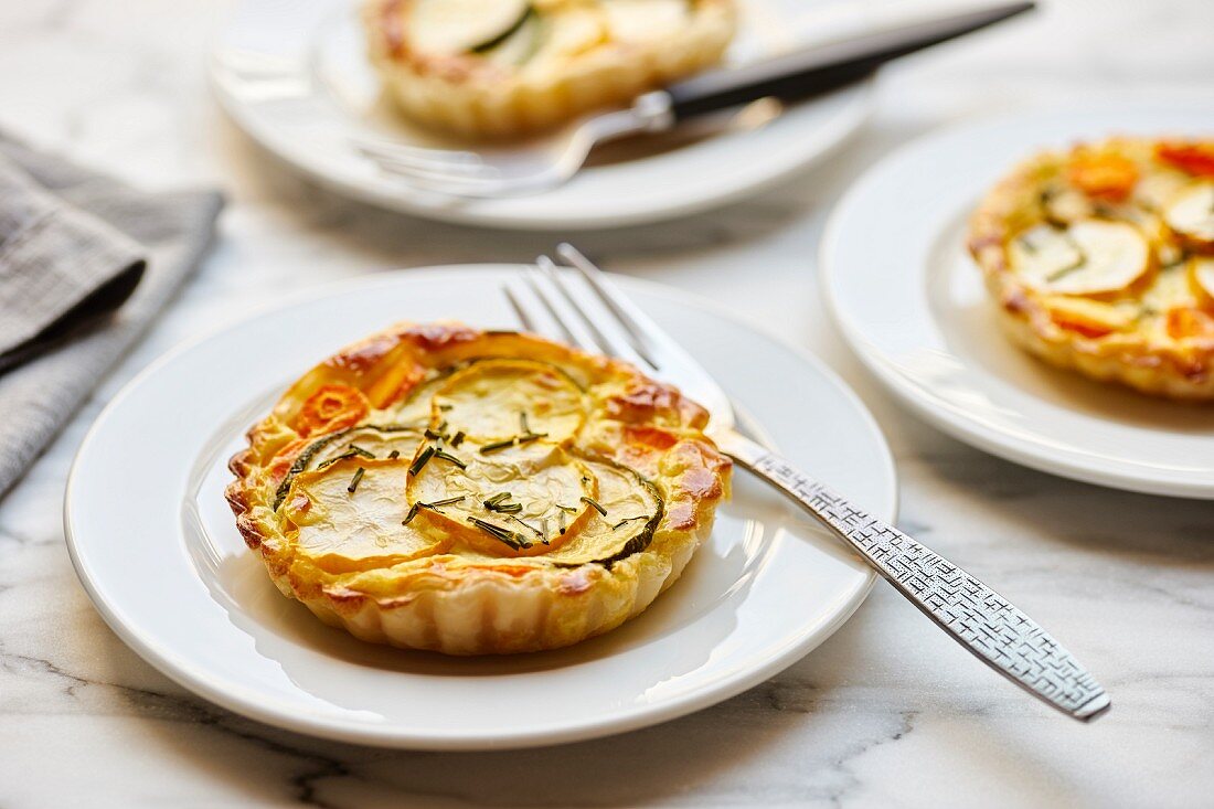 Puff pastry tarts with green and yellow zucchini and carrots