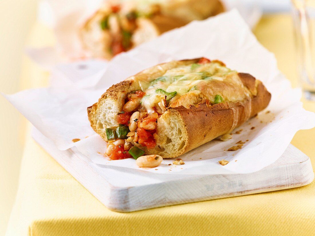 A baguette with beans, tomatoes and cheese