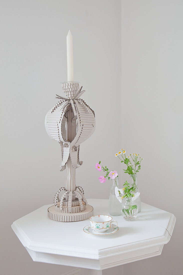 Candlestick made from corrugated cardboard on small white table