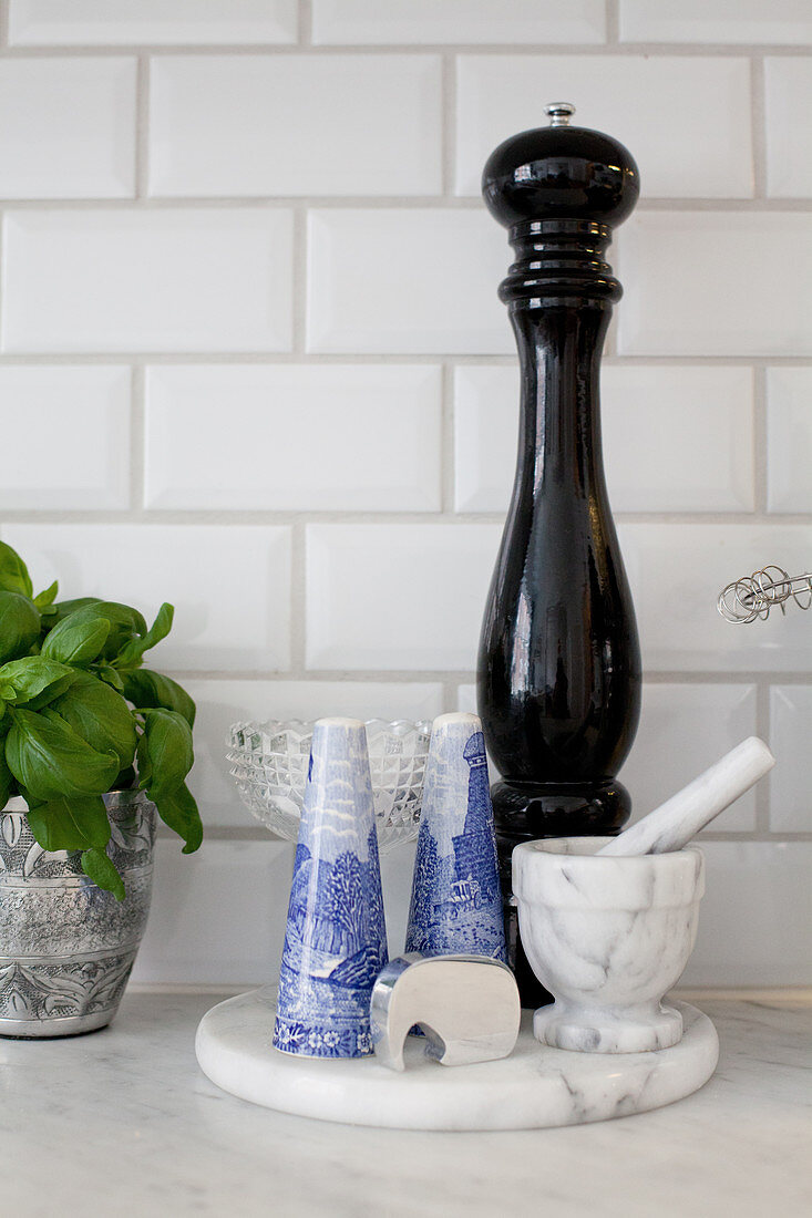 Pepper mill, pestle and mortar and salt cellars on marble board