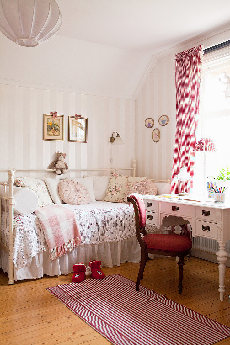 Red upholstered chair and antique desk next to charming in child's bedroom