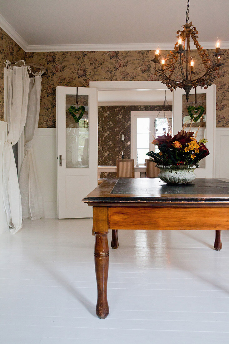 Chandelier above antique wooden table in foyer with white floor
