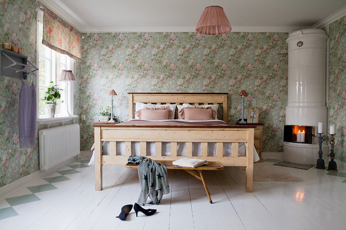 Swedish tiled stove in romantic bedroom with floral wallpaper