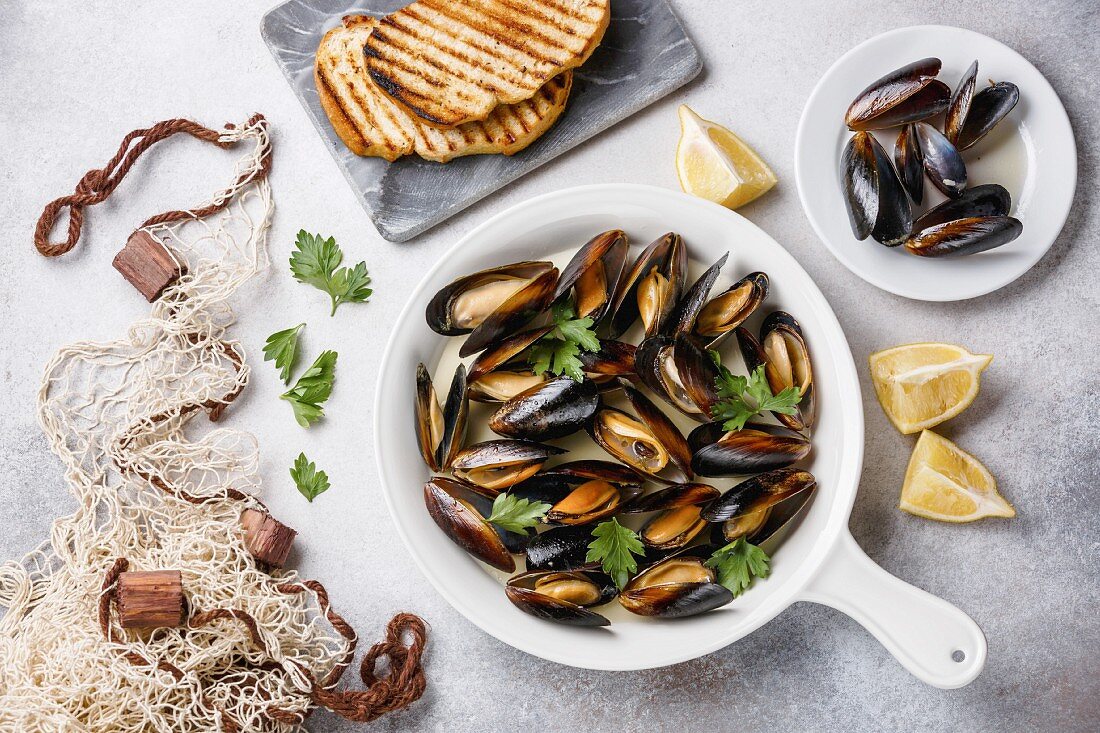 Miesmuscheln mit Petersilie in der Pfanne dazu Röstbrot (Aufsicht)