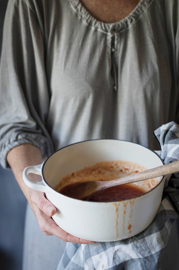 A woman holding a pan of homemade tomato jam