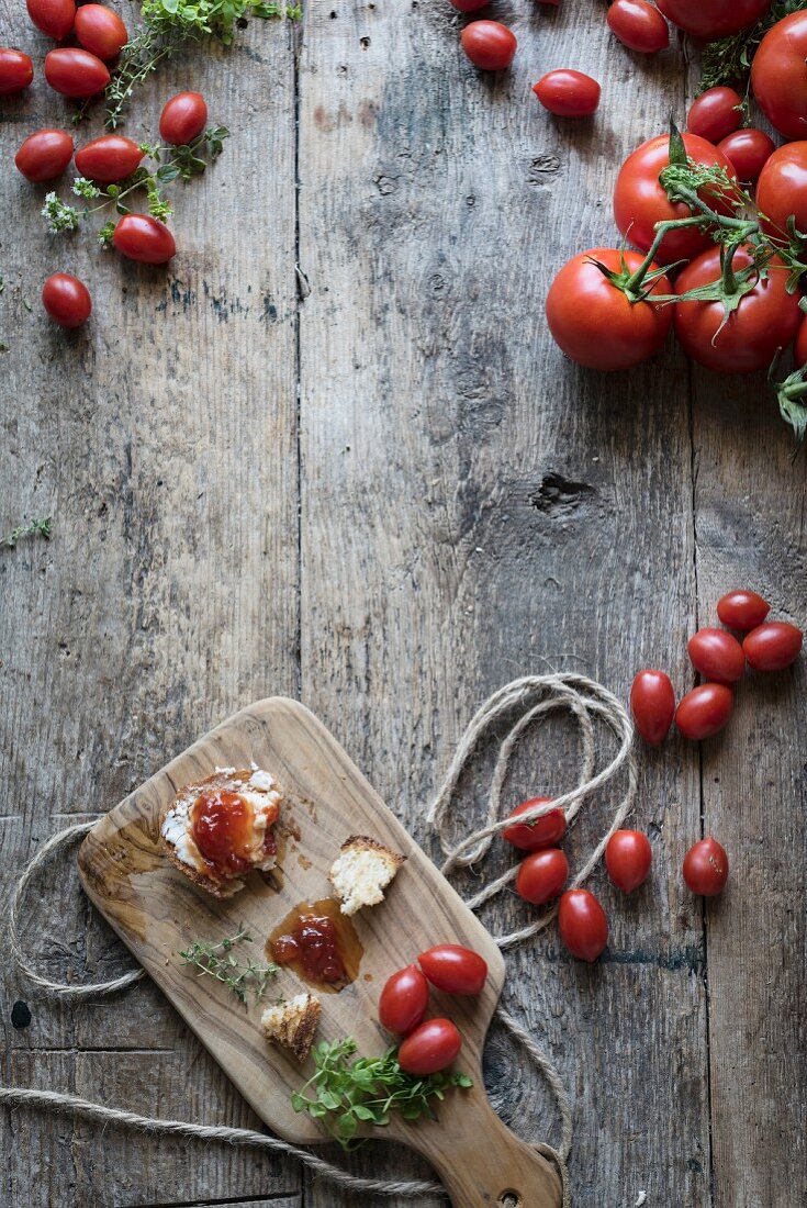 Brot mit Tomatenmarmelade auf Holzbrett daneben frische Tomaten