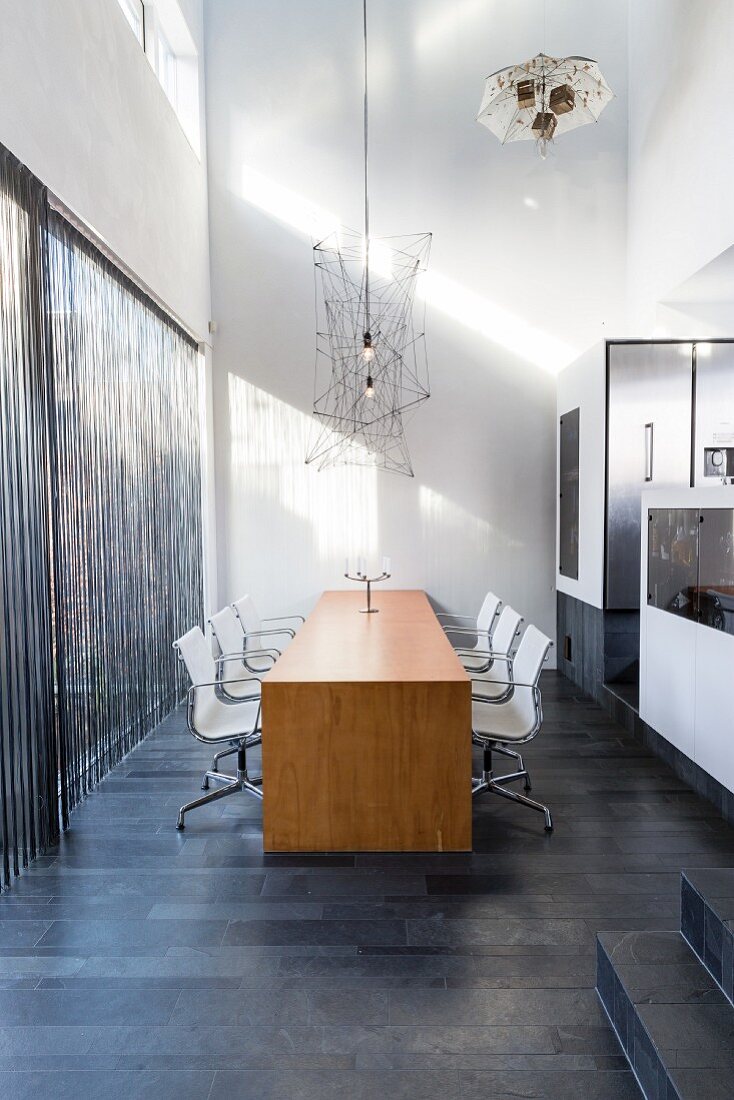 Wooden table and white chairs on charcoal-grey tiles floor