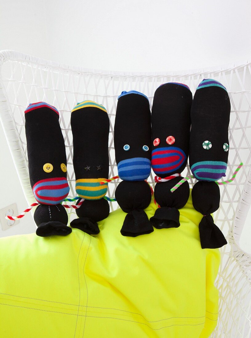 Black hand-made fabric dolls arranged on neon-yellow cushion