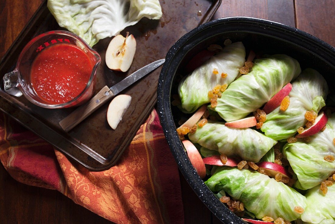 Stuffed cabbage in roasting pan with apple slices, rasins and tomato sauce