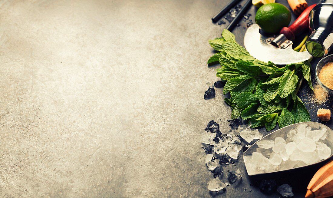 Mojito cocktail ingredients (fresh mint, lime, ice) on rustic background