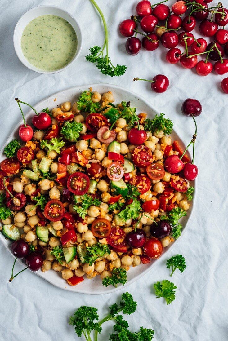 Chickpea salad with shredded carrot, cucumbers and cherries accompanied with a curry yogurt dressing