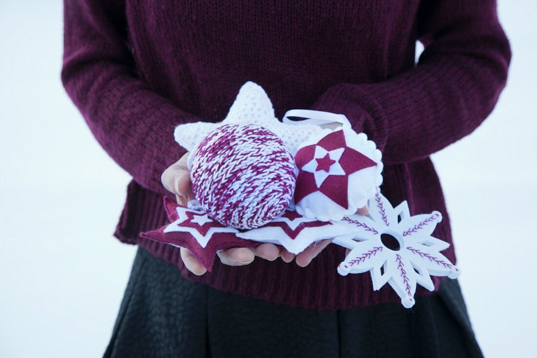 Hand-made Christmas tree decorations held in hands