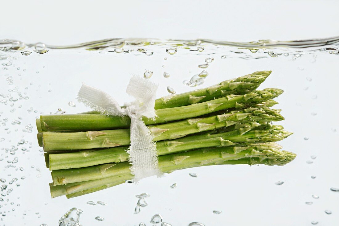 A bundle of asparagus in bubbly water