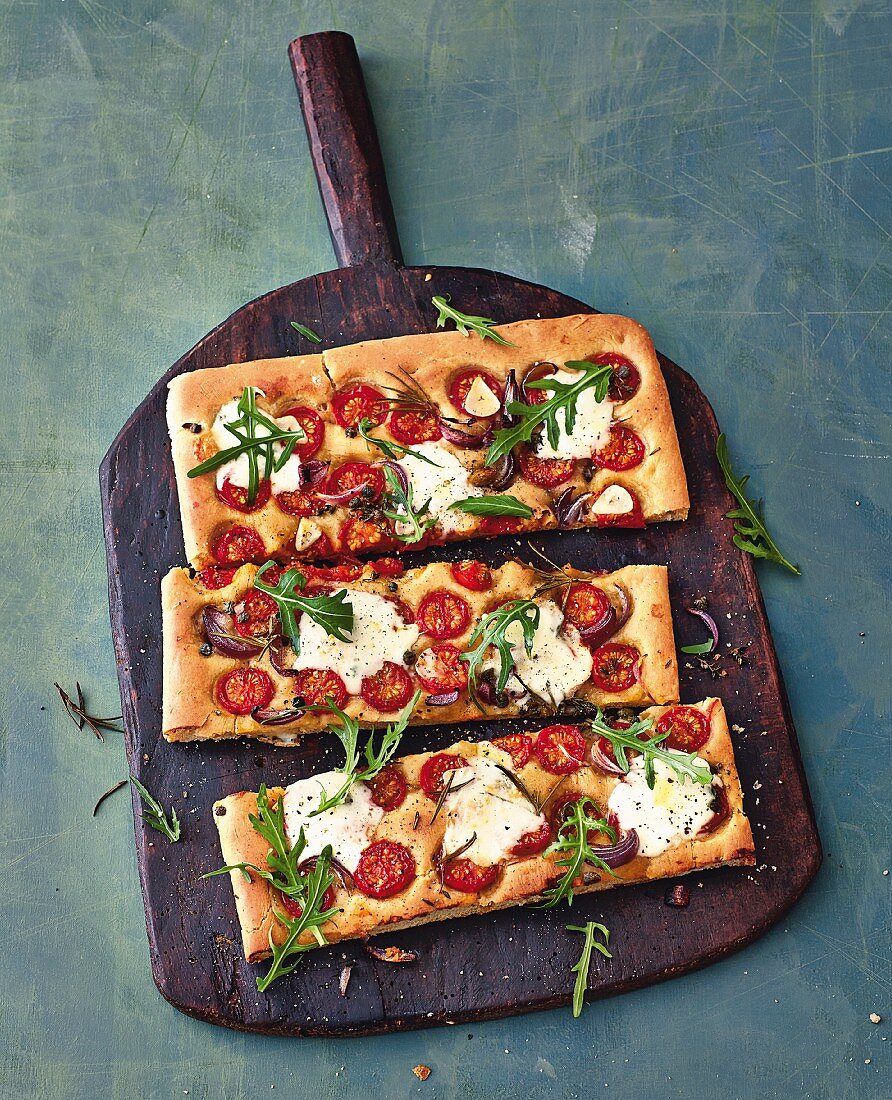 Focaccia with cherry tomatoes and taleggio on a wooden board