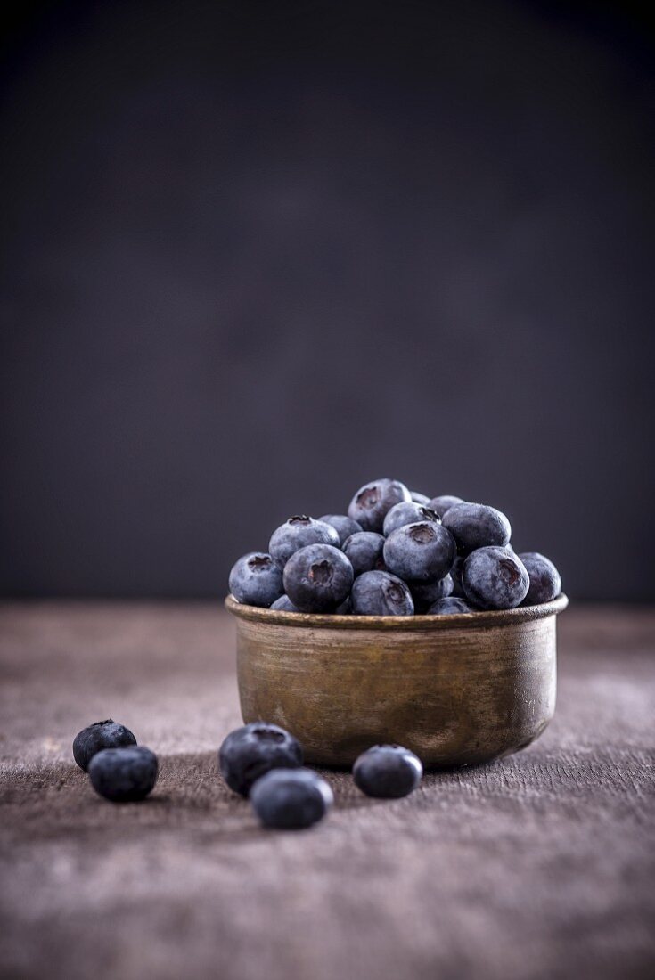 Blueberries in a metal bowl, black background