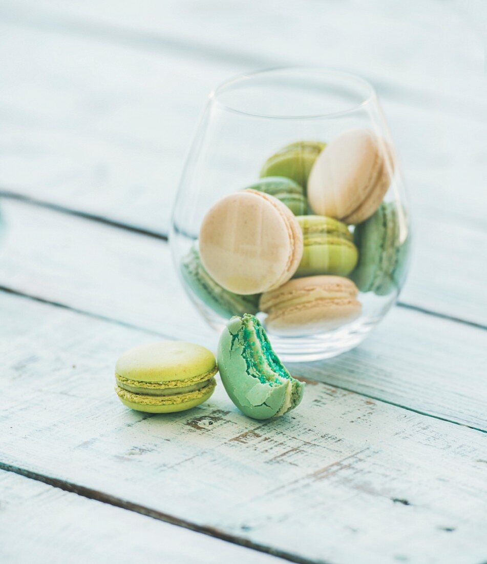 Colorful pastel pink, green and blue French macaron biscuits in glass over light blue painted wooden table