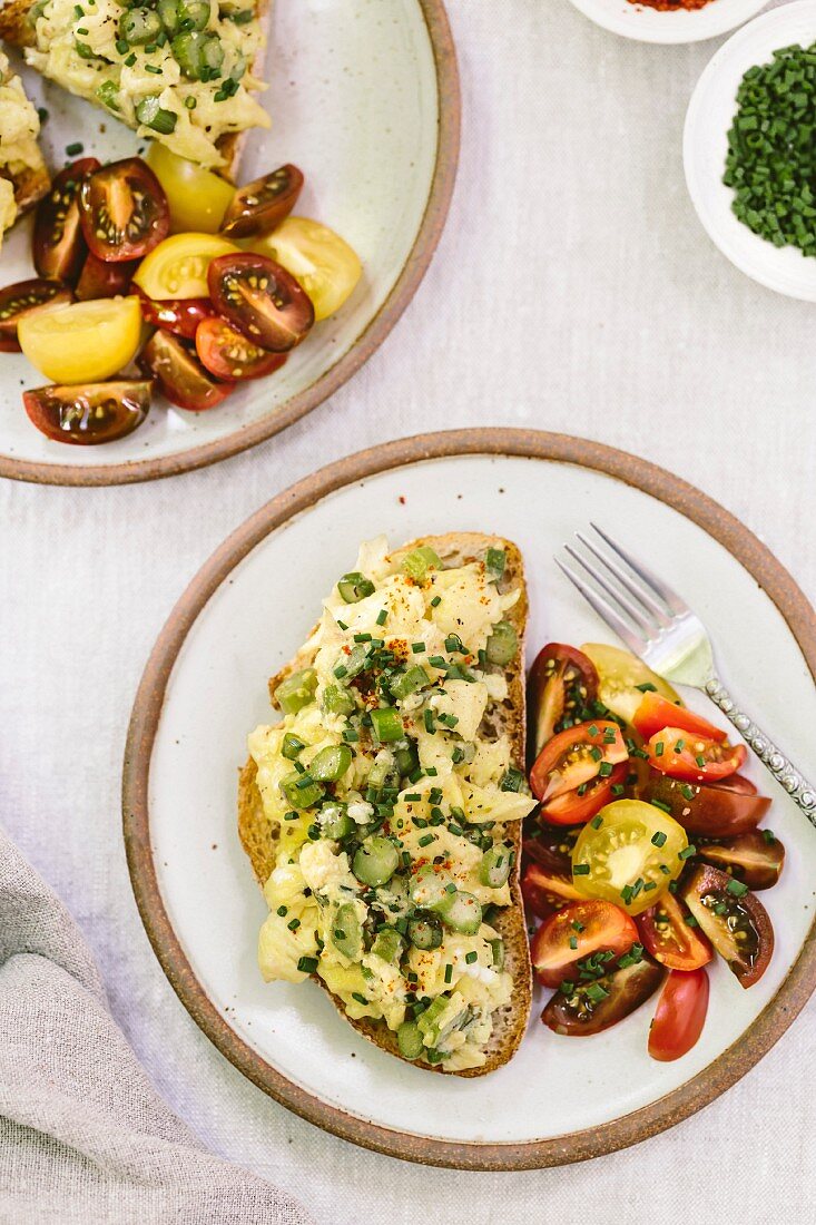 Getrüffeltes Rührei mit grünem Spargel auf Brot dazu Tomaten (Aufsicht)