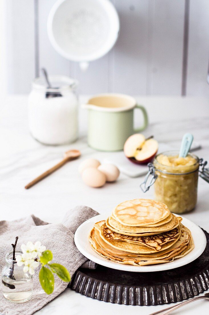 Stacked pancakes and a glass jar of apple sauce