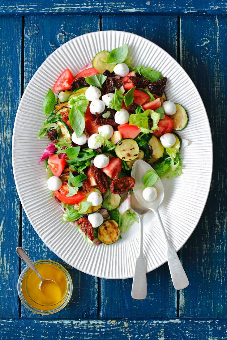 Salat mit gegrillter Zucchini, getrockneten und frischen Tomaten sowie Mozzarella