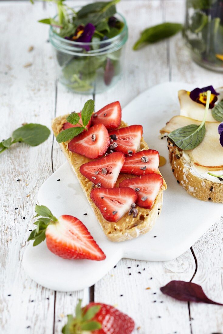 Open sandwiches topped with strawberries and peanut butter, and pear slices